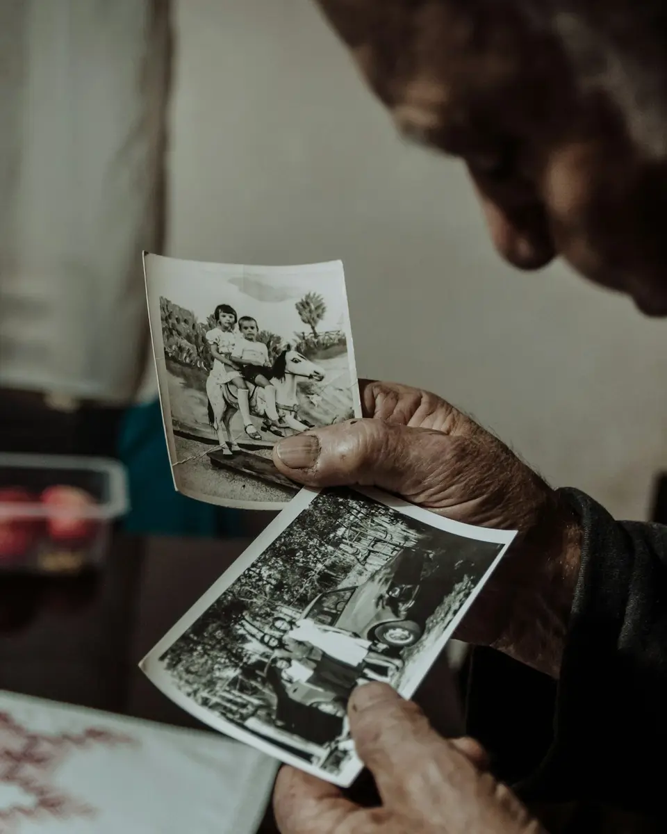An older man holding old family photographs